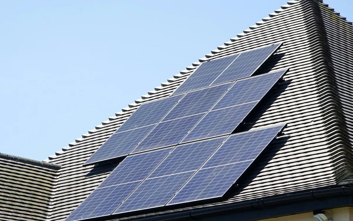 Tres hileras de placas solares fotovoltaicas montadas sobre la cubierta inclinada de una vivienda.