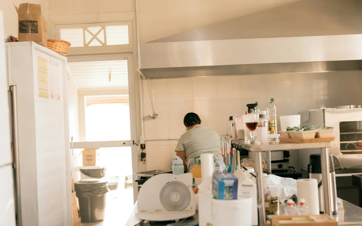 Cocina de obrador con amasadora, cortadora, horno y campana extractora de acero inoxidable.