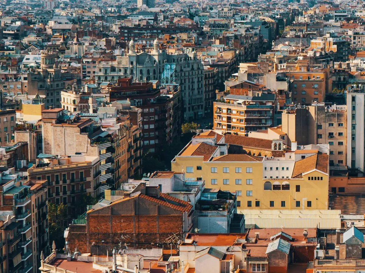Vista aérea de tejados, azoteas y terrazas de bloques de viviendas de una ciudad española, con la luz del atardecer.