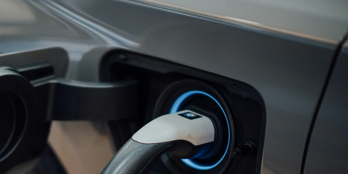 Cable de recarga conectado a la toma de un coche eléctrico, con el anillo indicador iluminado.