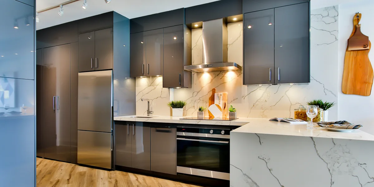 Cocina de una vivienda con frigorífico, horno, placa de inducción y campana extractora encendida.