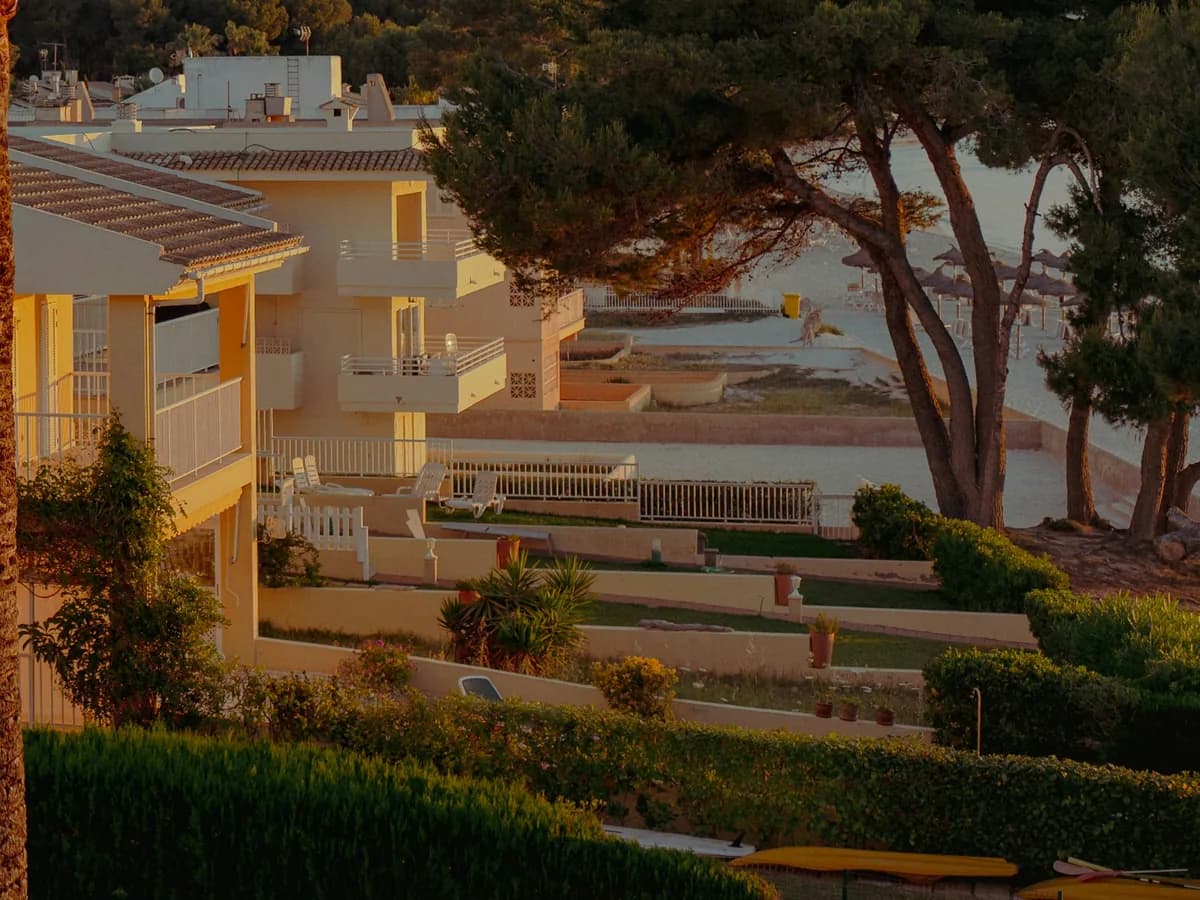 Apartamentos de una urbanización de costa española al atardecer, con las terrazas vacías y las tumbonas recogidas frente al mar.