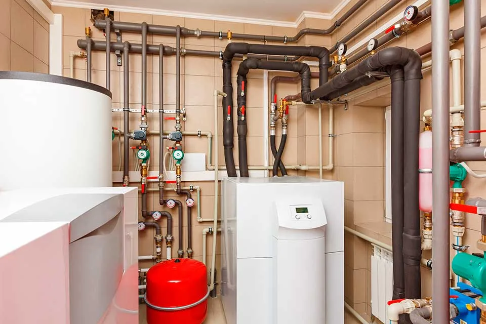Sala de máquinas con una bomba de calor, depósito de inercia, vaso de expansión y tuberías aisladas